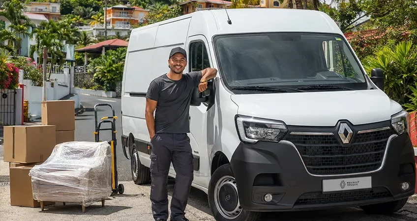 Fourgon Renault Master blanc chargé avec cartons, déménageur souriant devant avec vue sur les montagnes de La Réunion