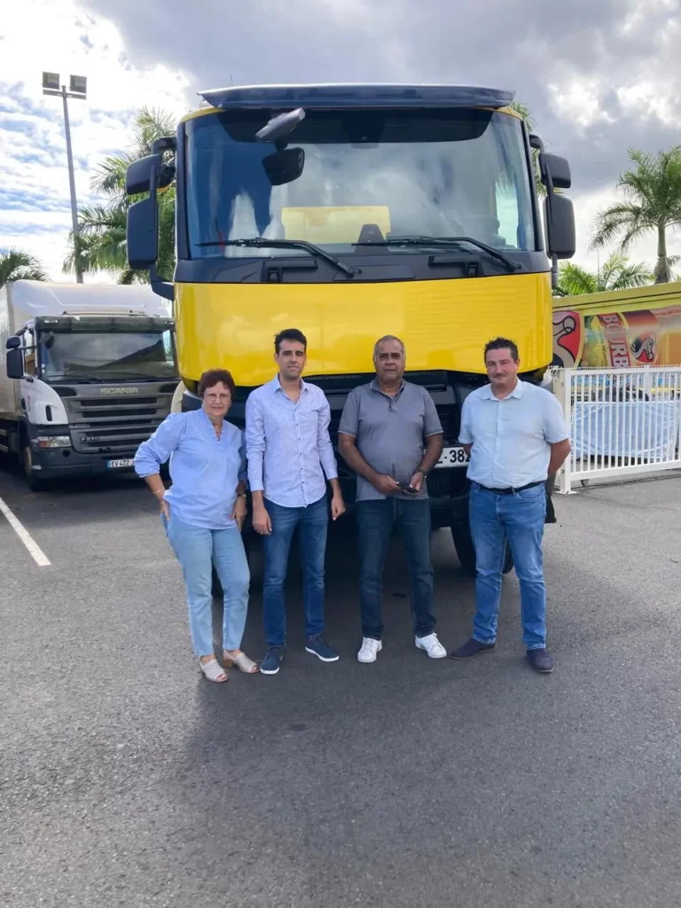 Remise d'un premier camion Renault Trucks jaune à un client à La Réunion, entouré de l'équipe de la concession